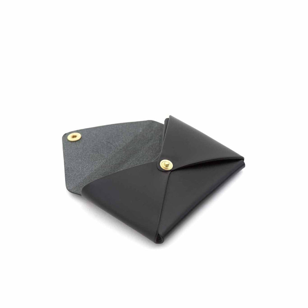The interior of a black leather business card holder with a brass snap button closure.