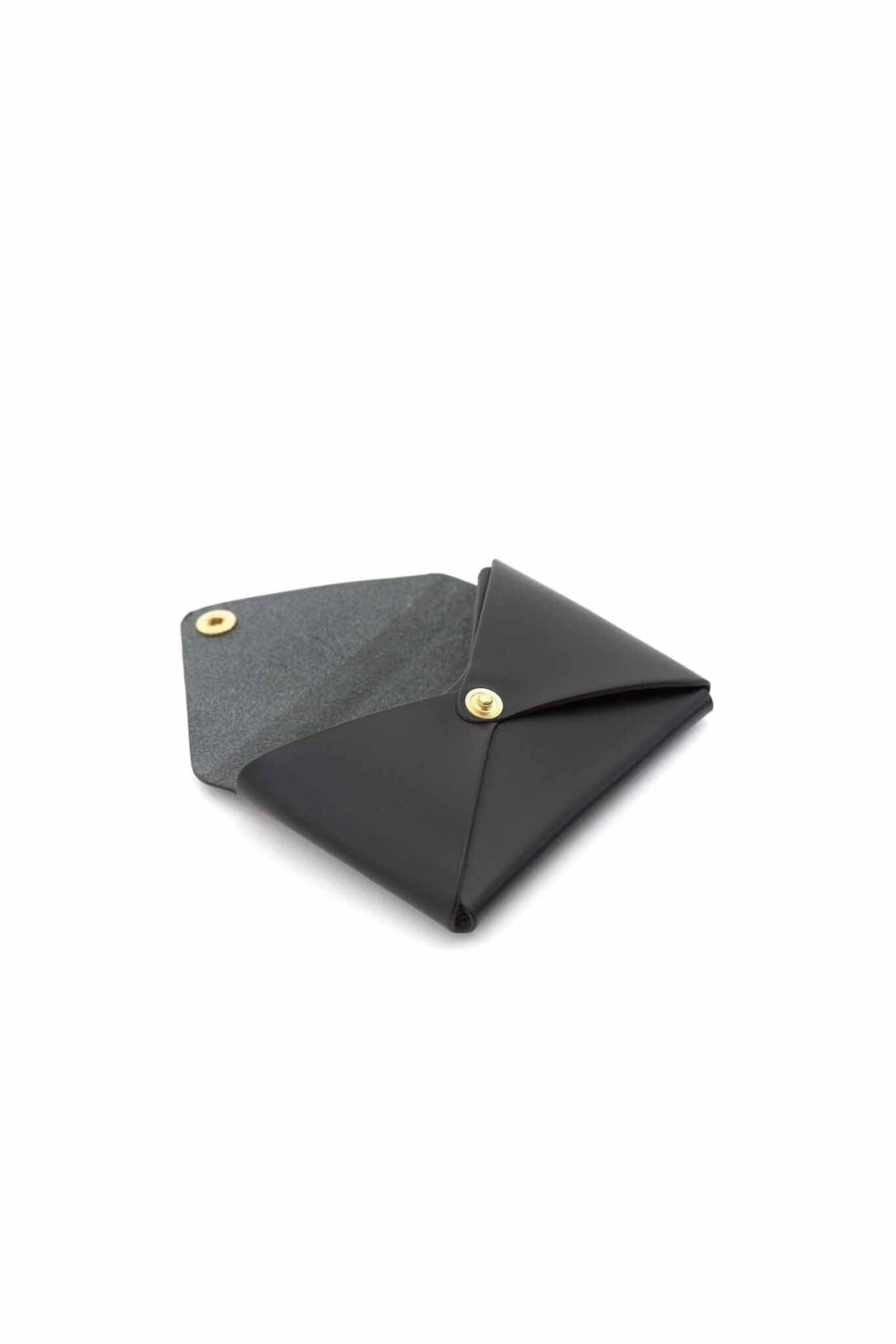 The interior of a black leather business card holder with a brass snap button closure.