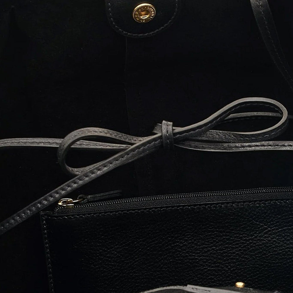 
                  
                    Close-up of a black leather bag with a drawstring and gold accents.
                  
                