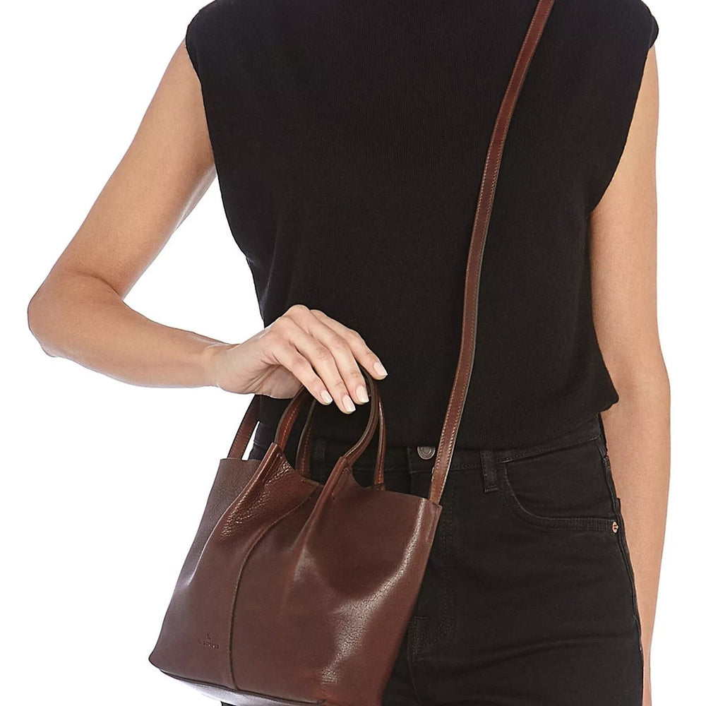 
                  
                    Woman wearing a small brown crossbody leather bag
                  
                