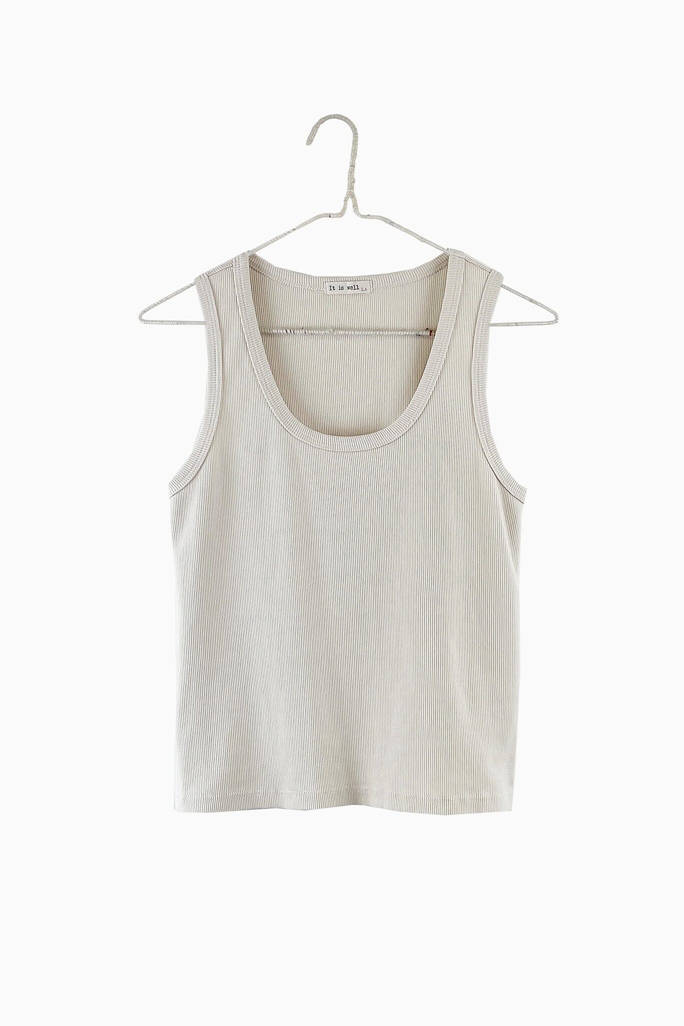 Beige tank top on a hanger against a white background