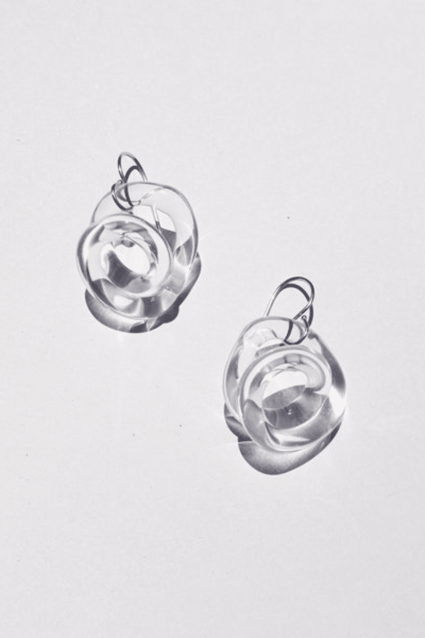 A pair of clear glass squiggle hoops with a silver fish hook ear wire.