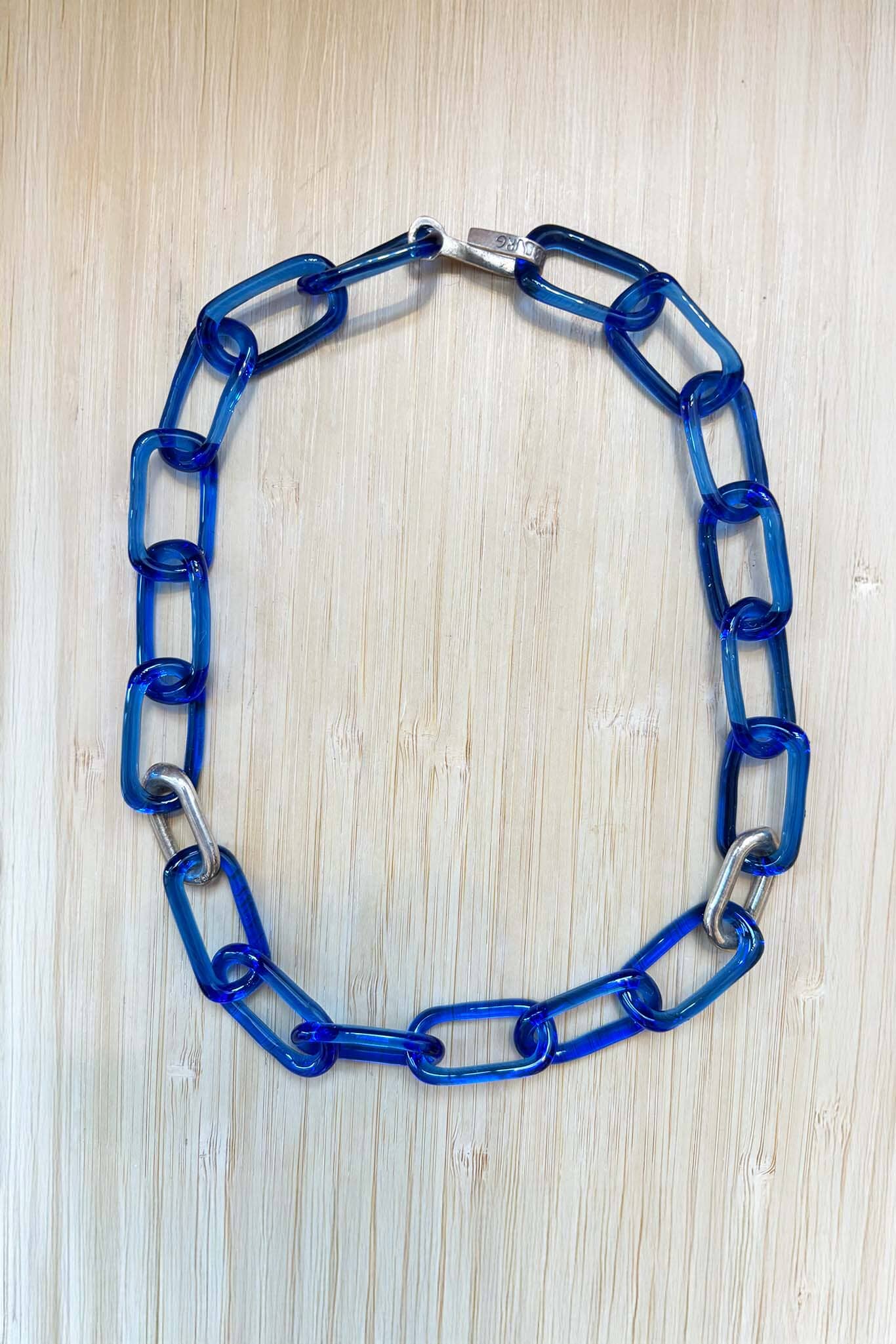 Blue glass chain necklace on a light wood surface