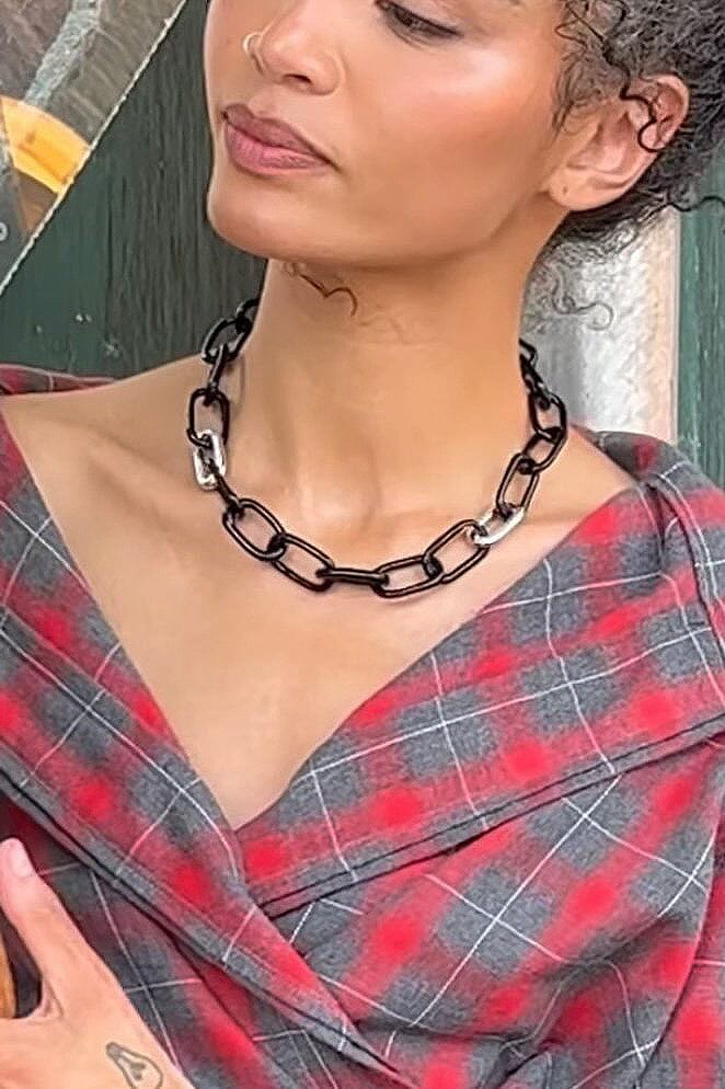 A model wearing a a black oval glass link necklace