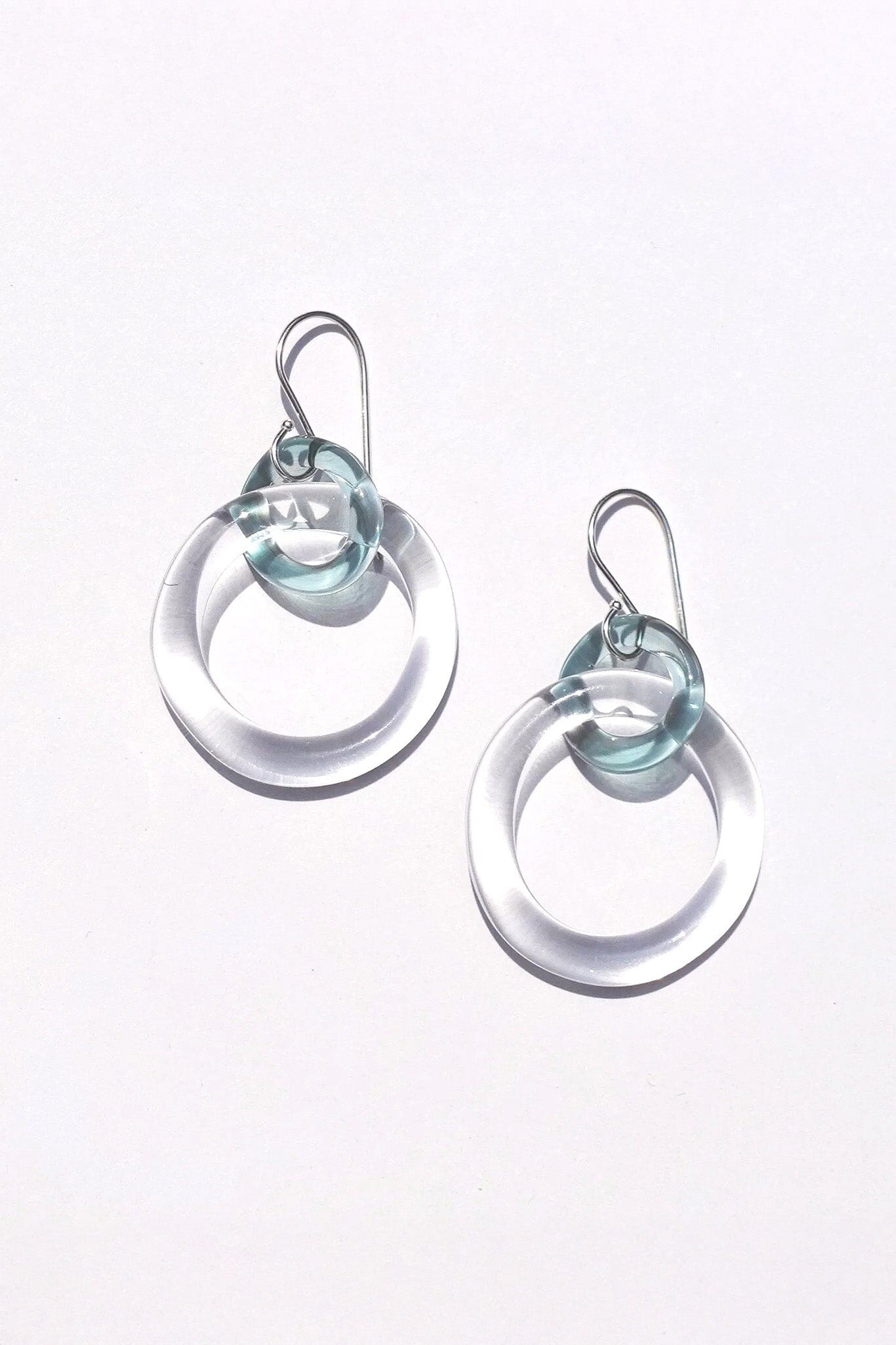 Pair of clear and glacier glass hoop earrings on a white background