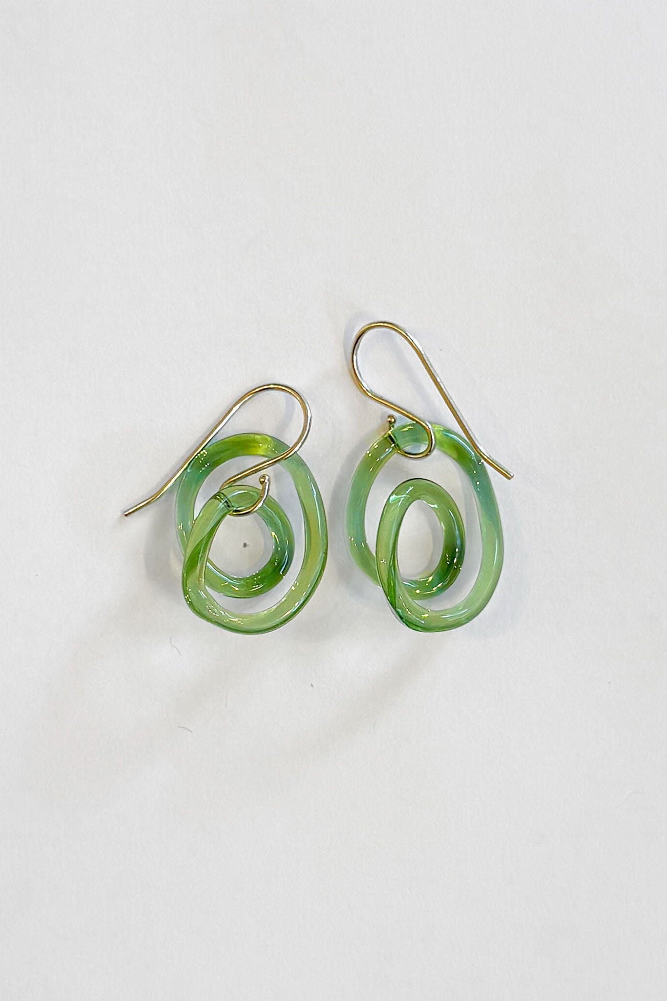 Green glass spiral earrings on a white background