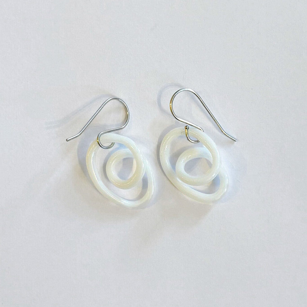 Pair of white glass spiral earrings on a light gray background