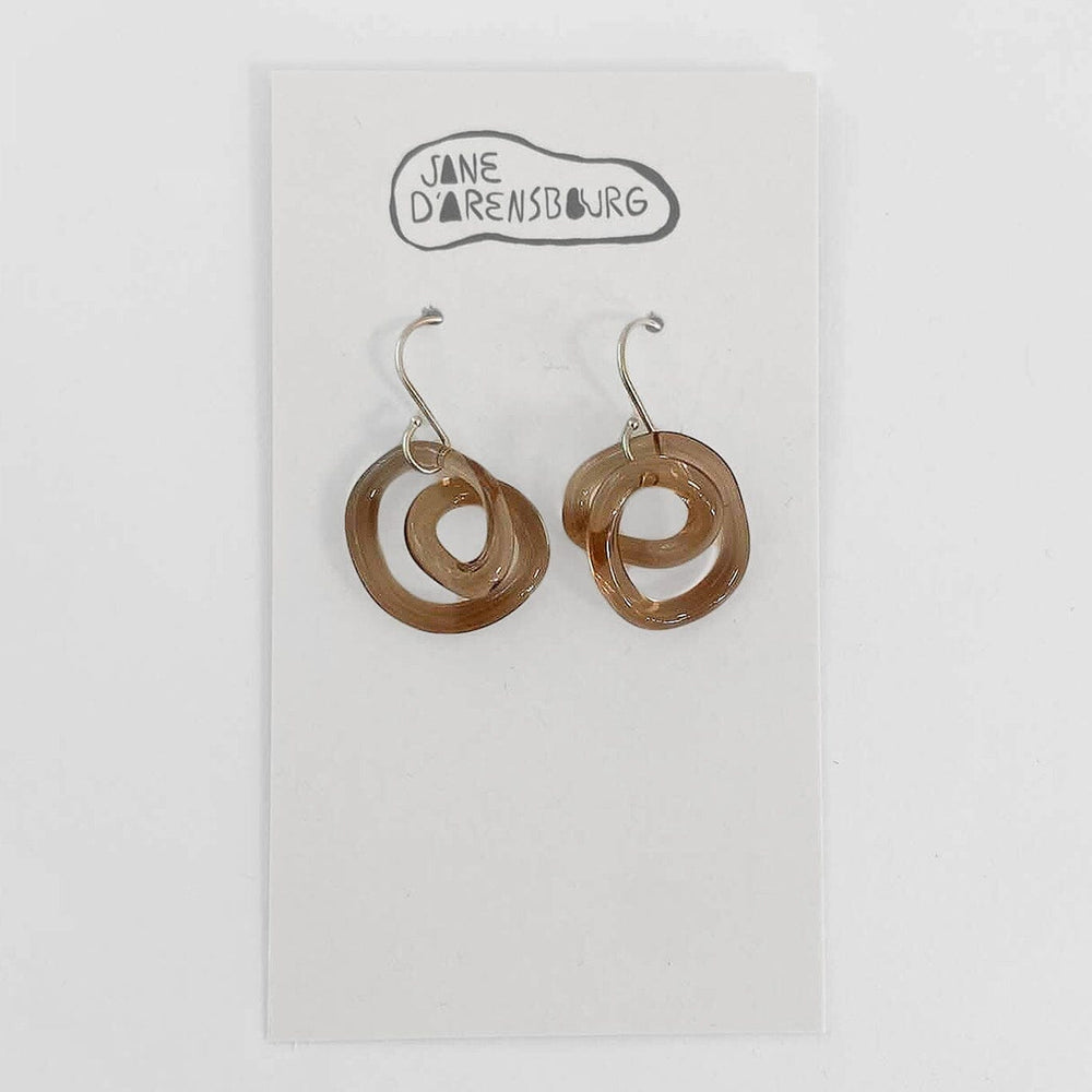 A pair of brown glass small squiggle earrings in mauve color with sterling silver earring wires, displayed on a white card with 'Jane D'Arensbourg' branding.
