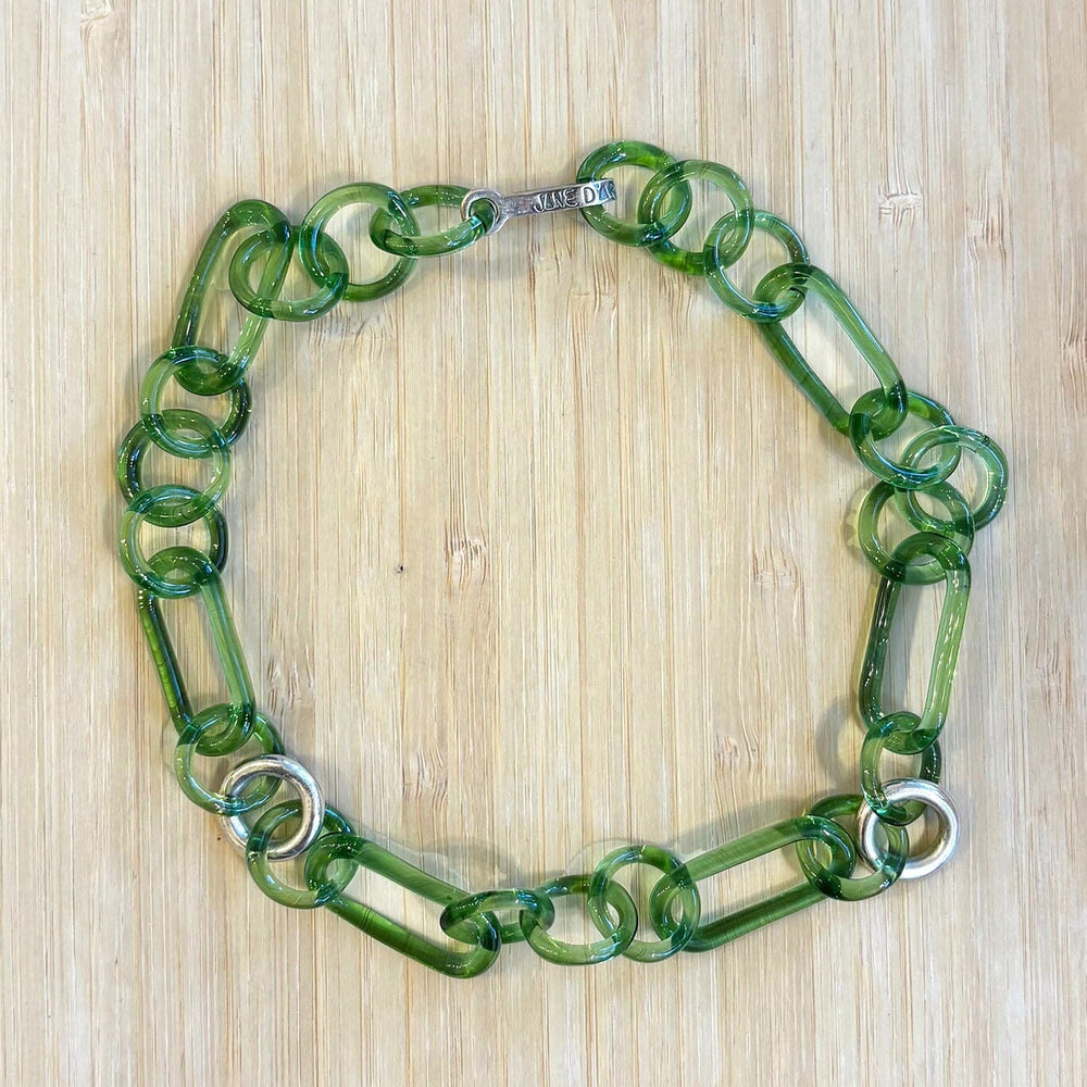 Green glass necklace with sterling silver accents on a wooden surface