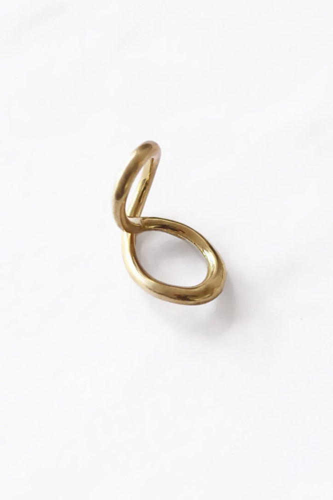 A gold-colored brass ring with a mobius twist design, displayed against a white background.