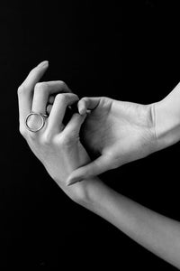 Black and white photo of two hands with a circular ring on a black background