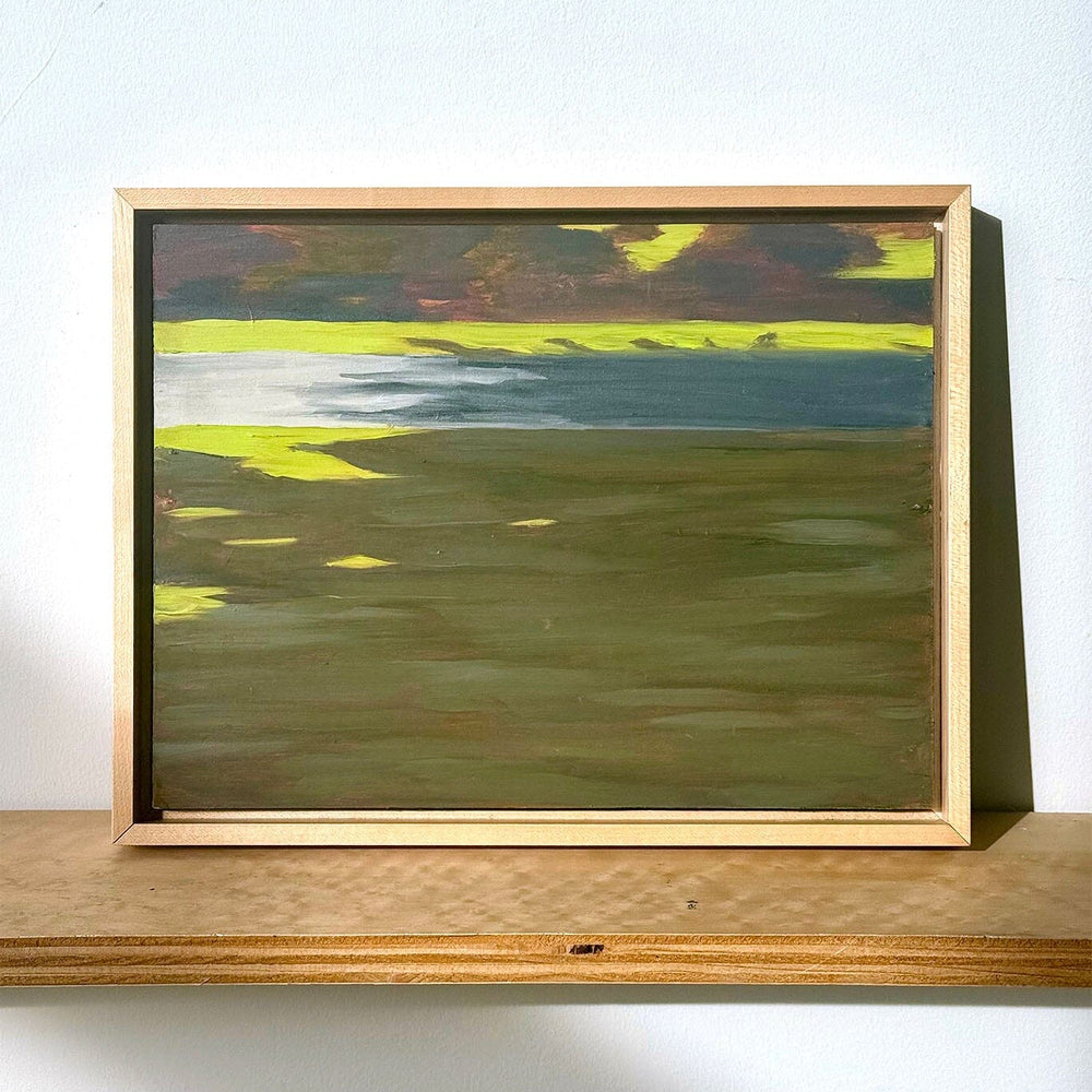 Framed abstract painting on a wooden shelf against a white wall