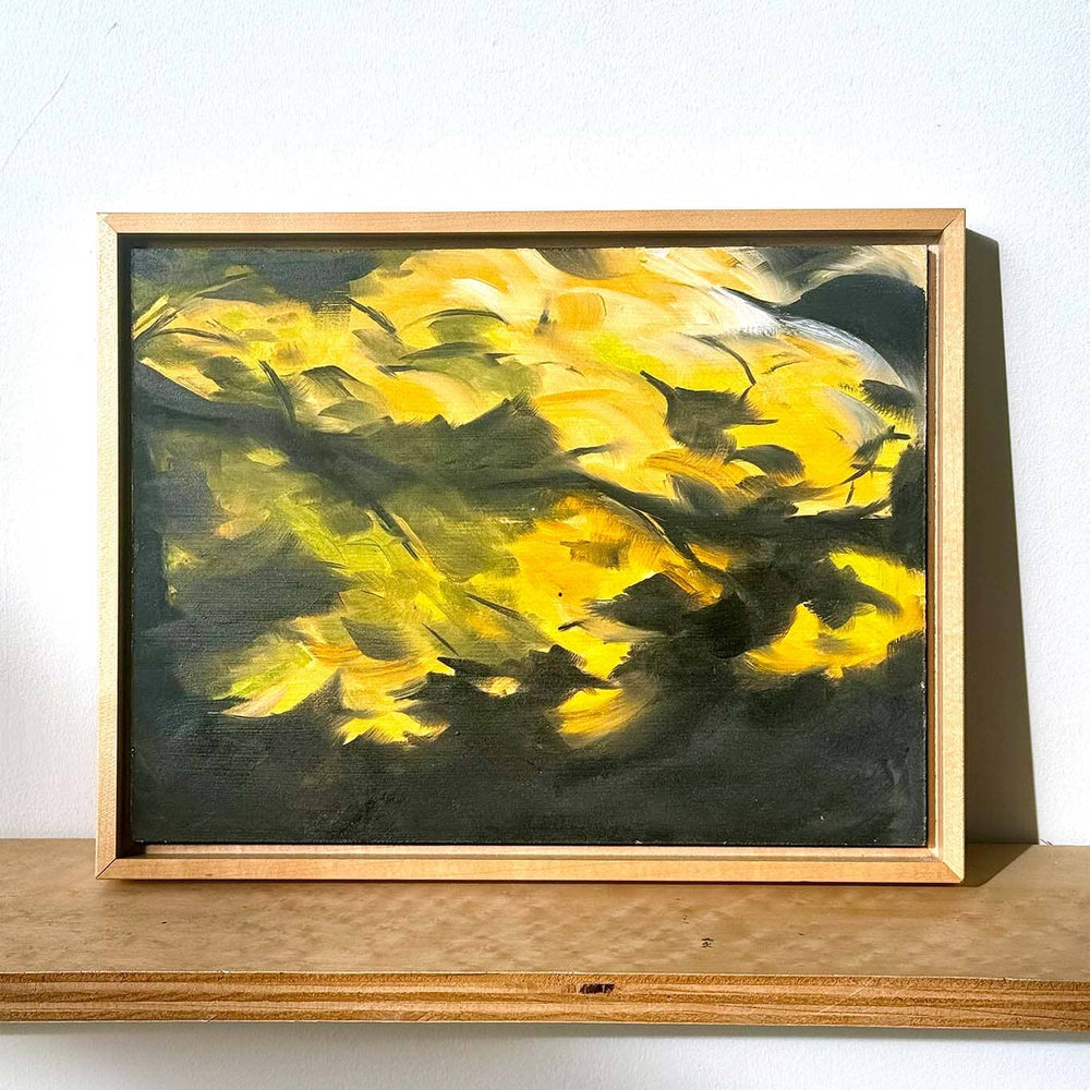 Framed painting with yellow abstract design on a white wall