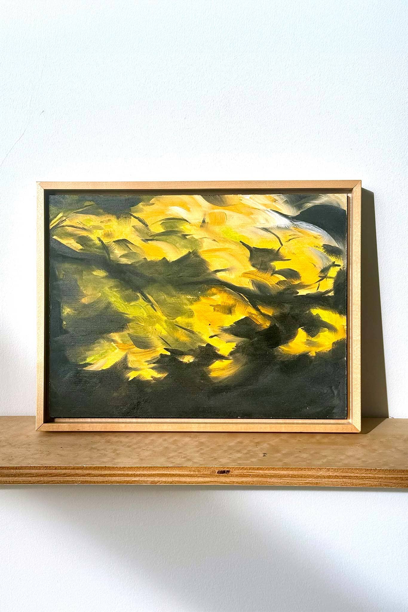 Framed painting with yellow abstract design on a white wall