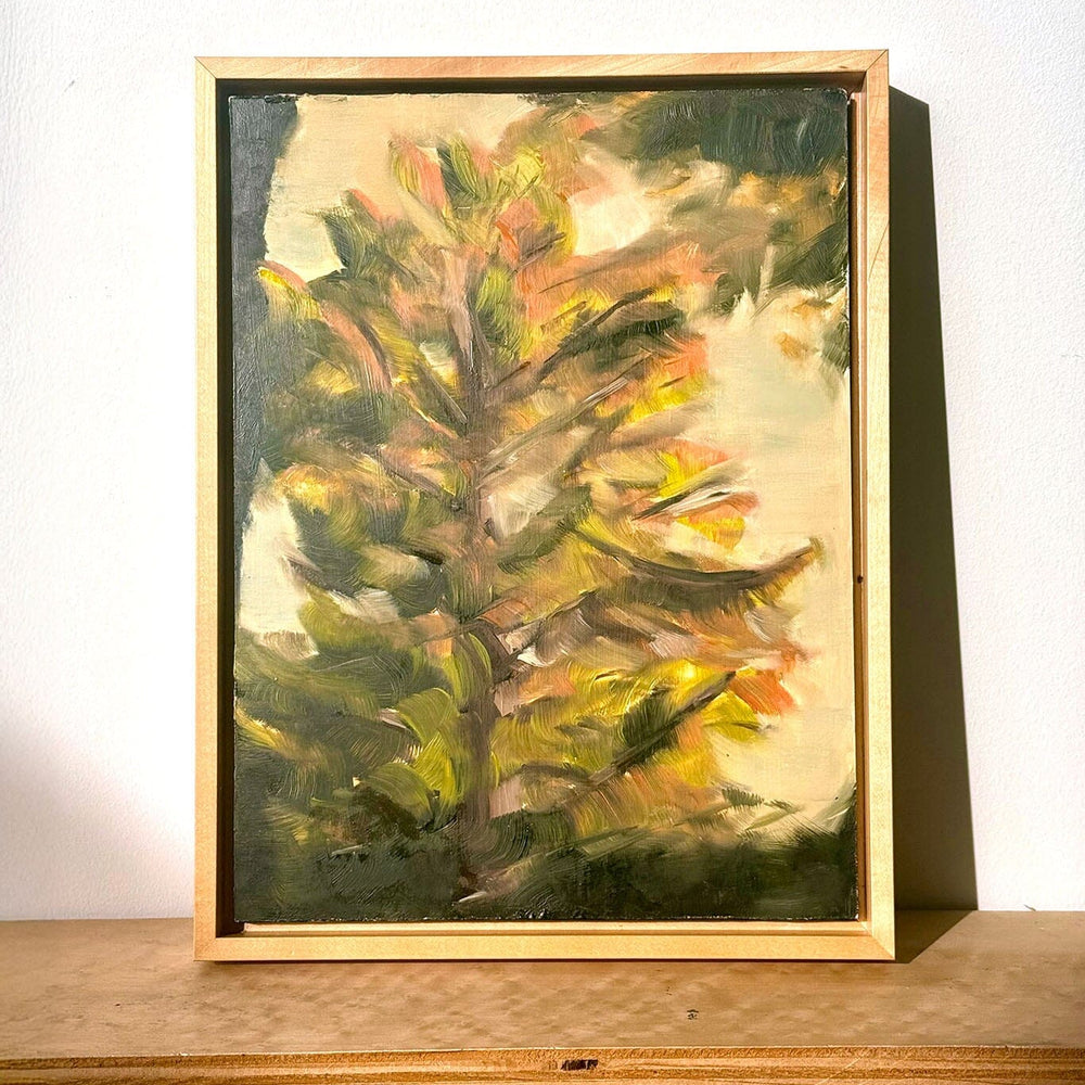 Framed painting of a tree on a wooden shelf with a white background