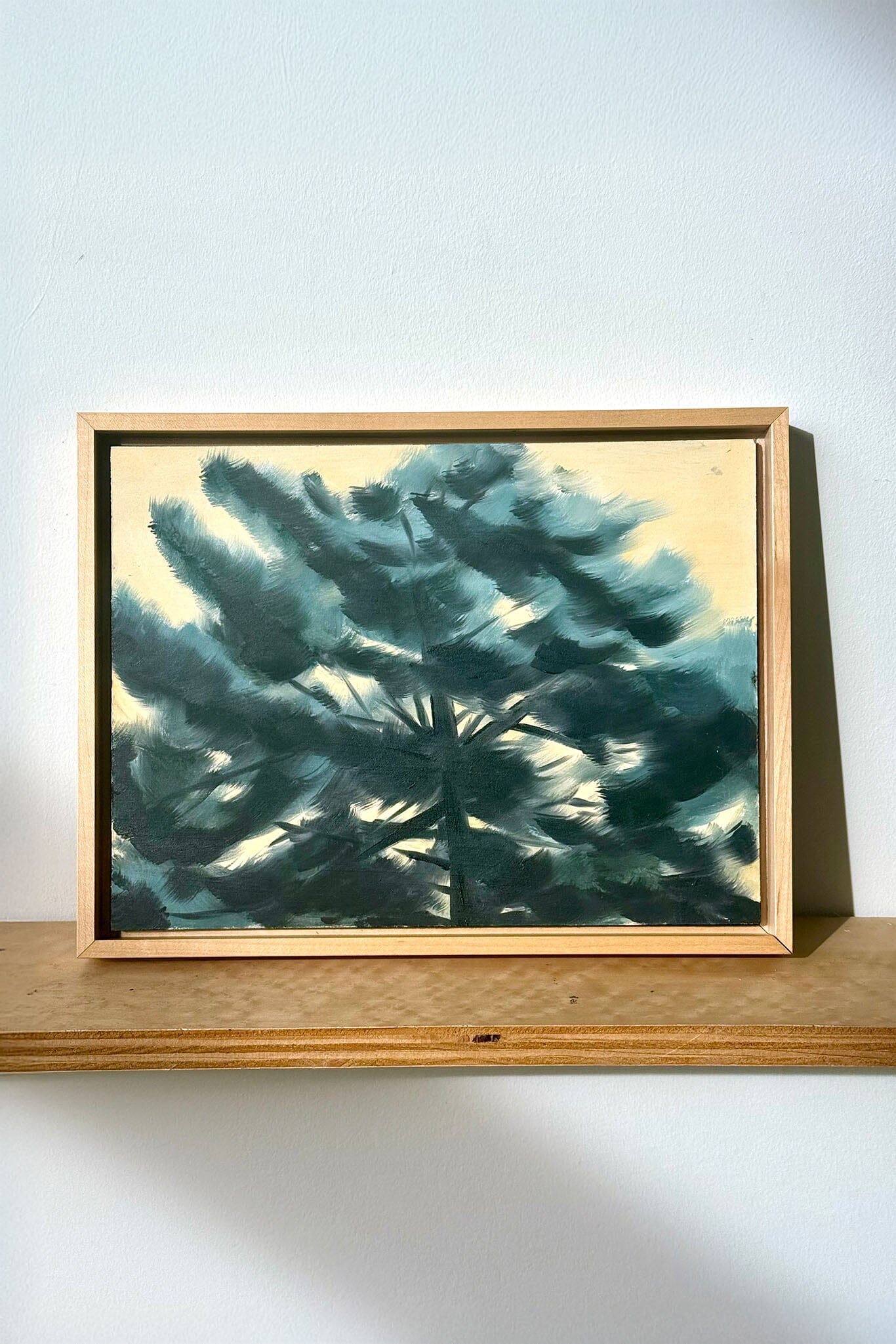 Framed artwork of a teal abstract design on a white wall