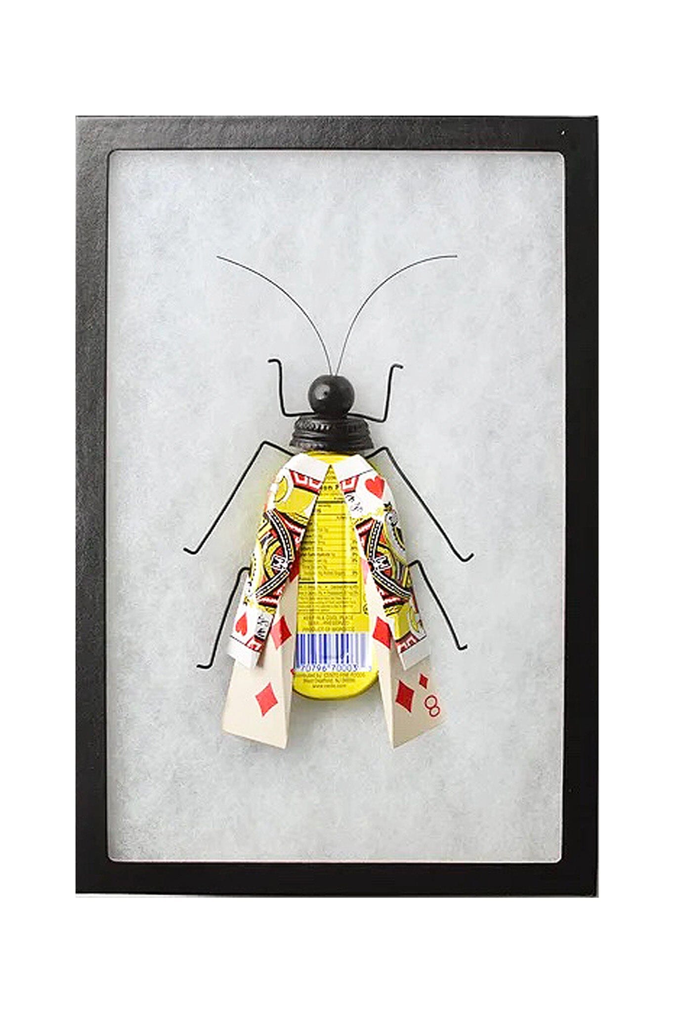 Framed artwork of a paper insect with playing card wings on a white background