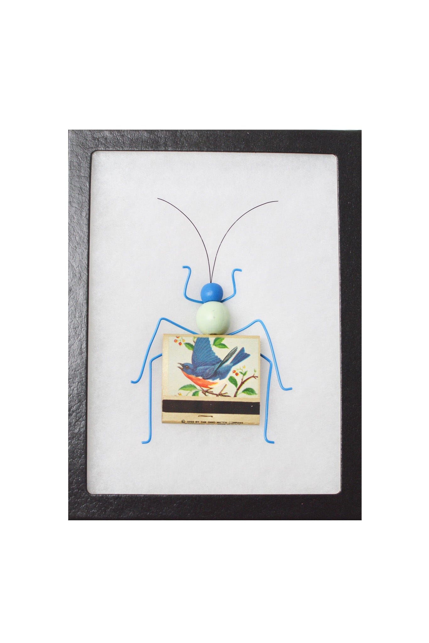 Framed artwork of a blue bug made from matches on a white background