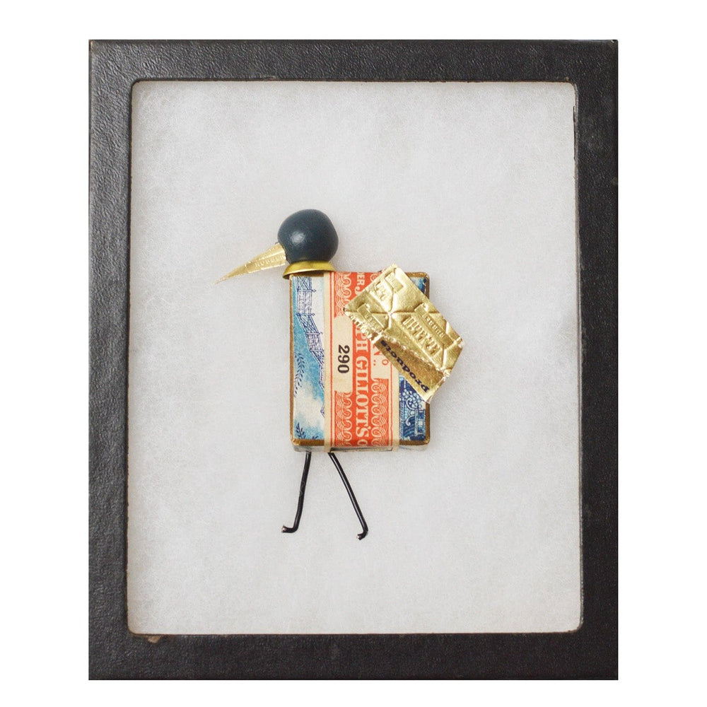 Small bird figurine displayed in a black frame.