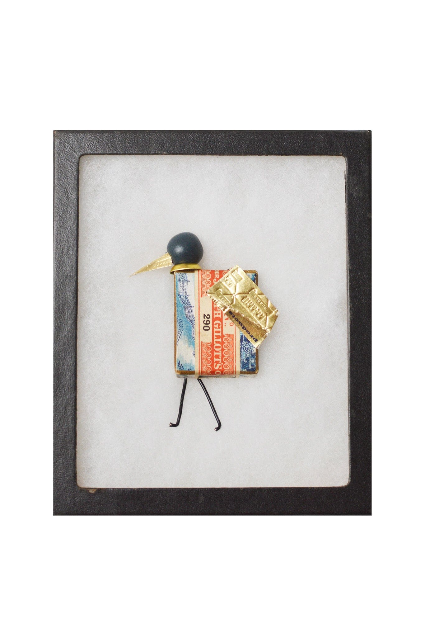 Small bird figurine displayed in a black frame.