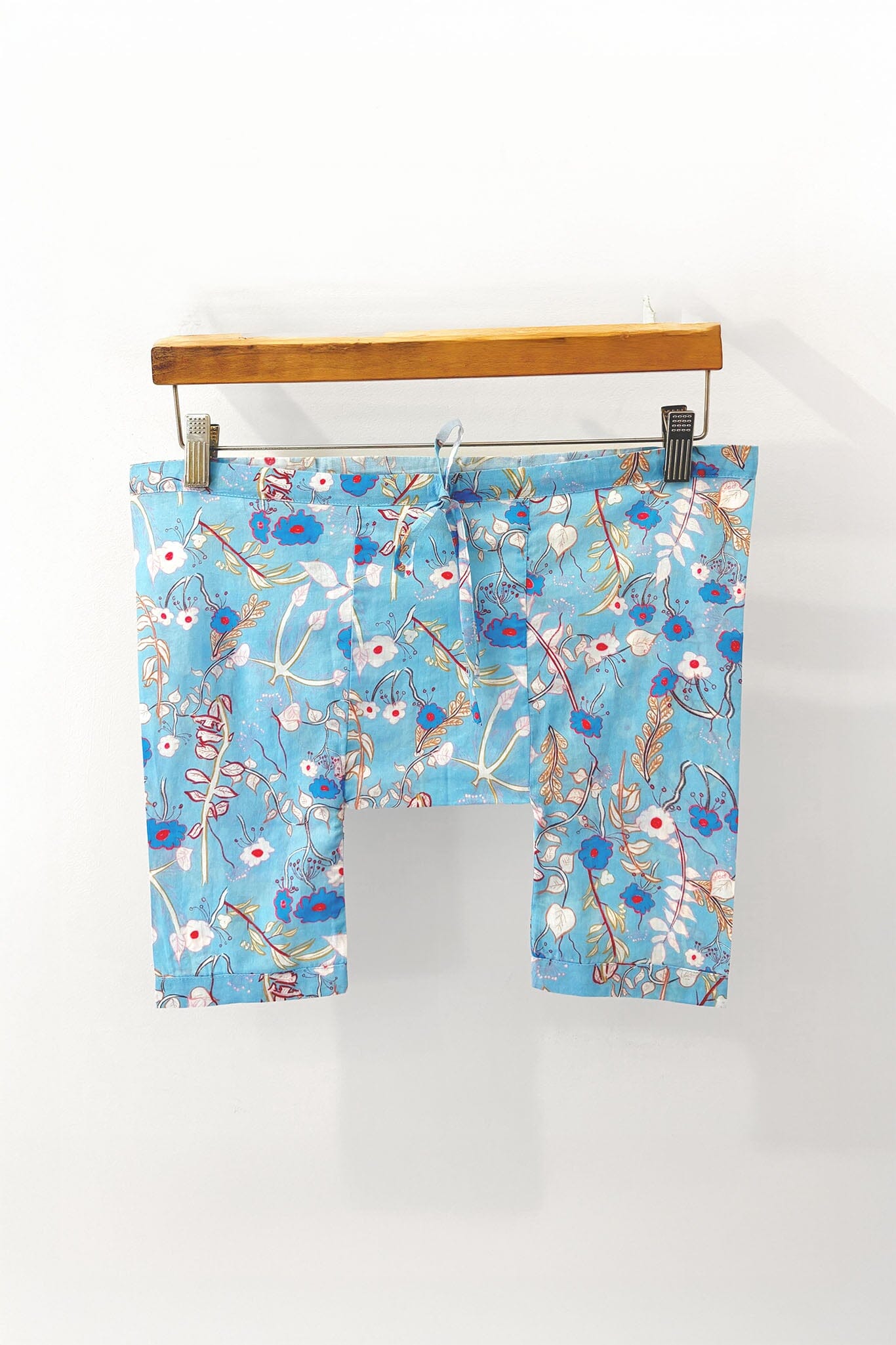 Children's blue floral pajama bottoms on a hanger against a white background