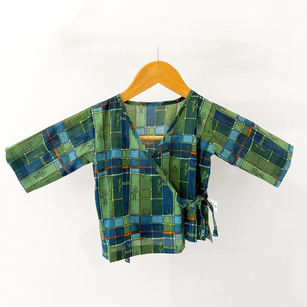 Green and blue checkered baby pajama top on a wooden hanger against a white background
