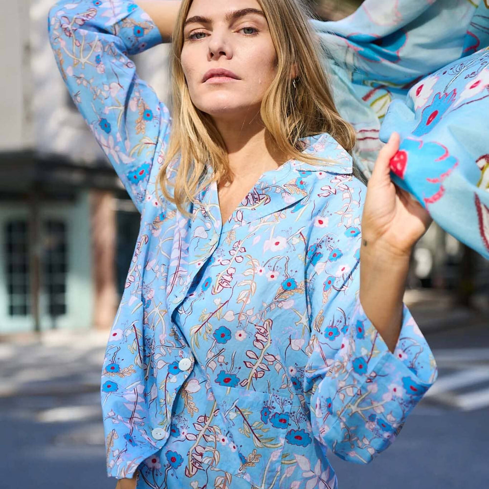A woman wears blue, long sleeve floral cotton pajamas