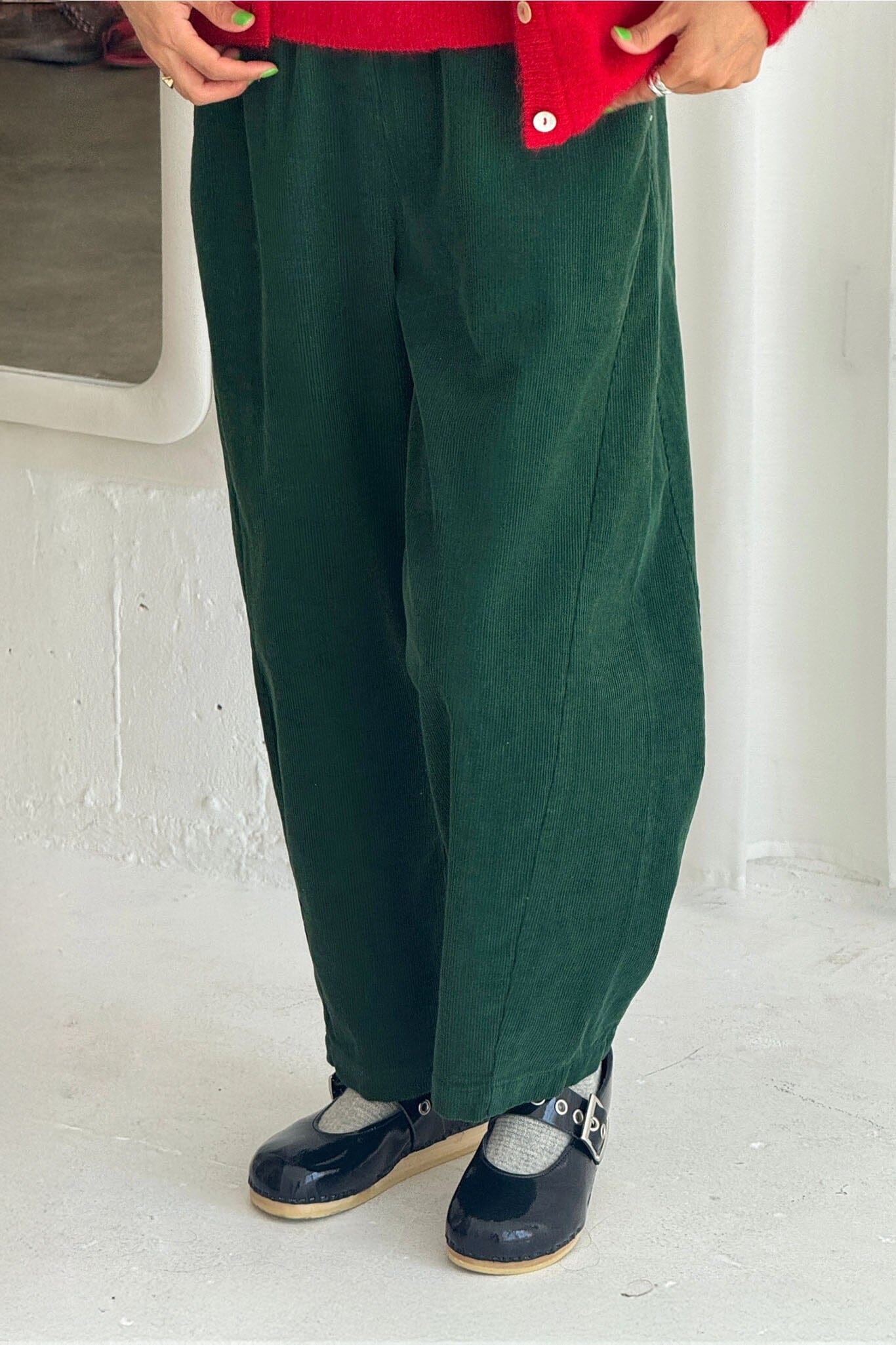 Person wearing green pants and a red shirt with a white background