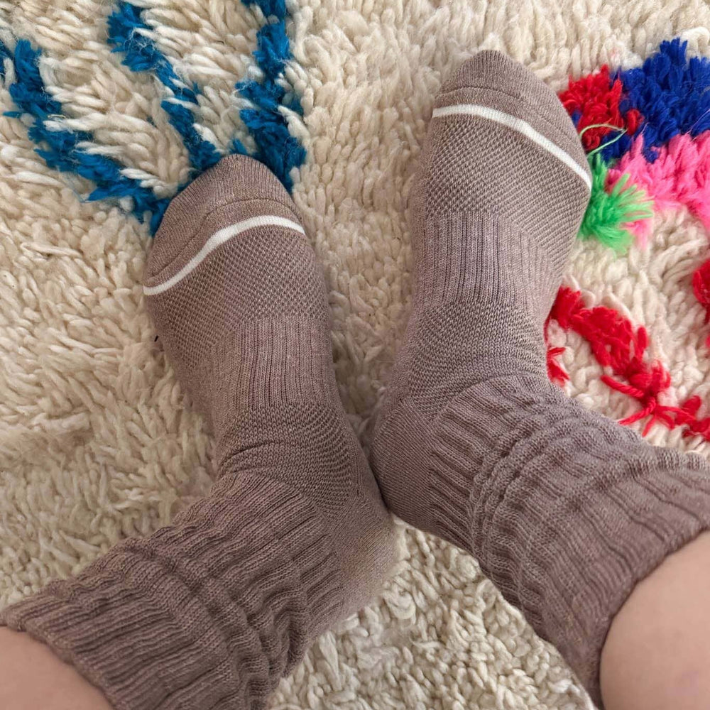 Brown socks on a textured rug with colorful patterns