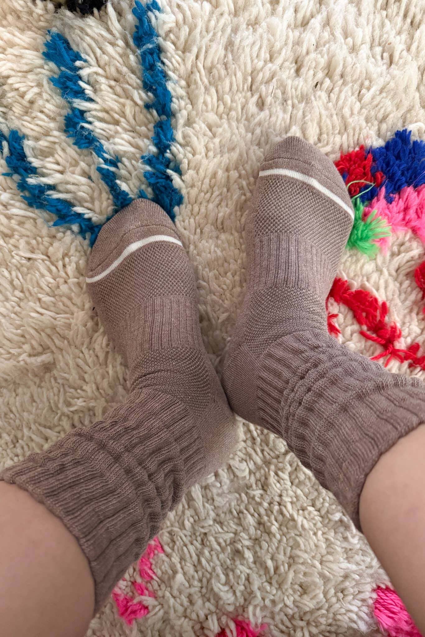 Brown socks on a textured rug with colorful patterns
