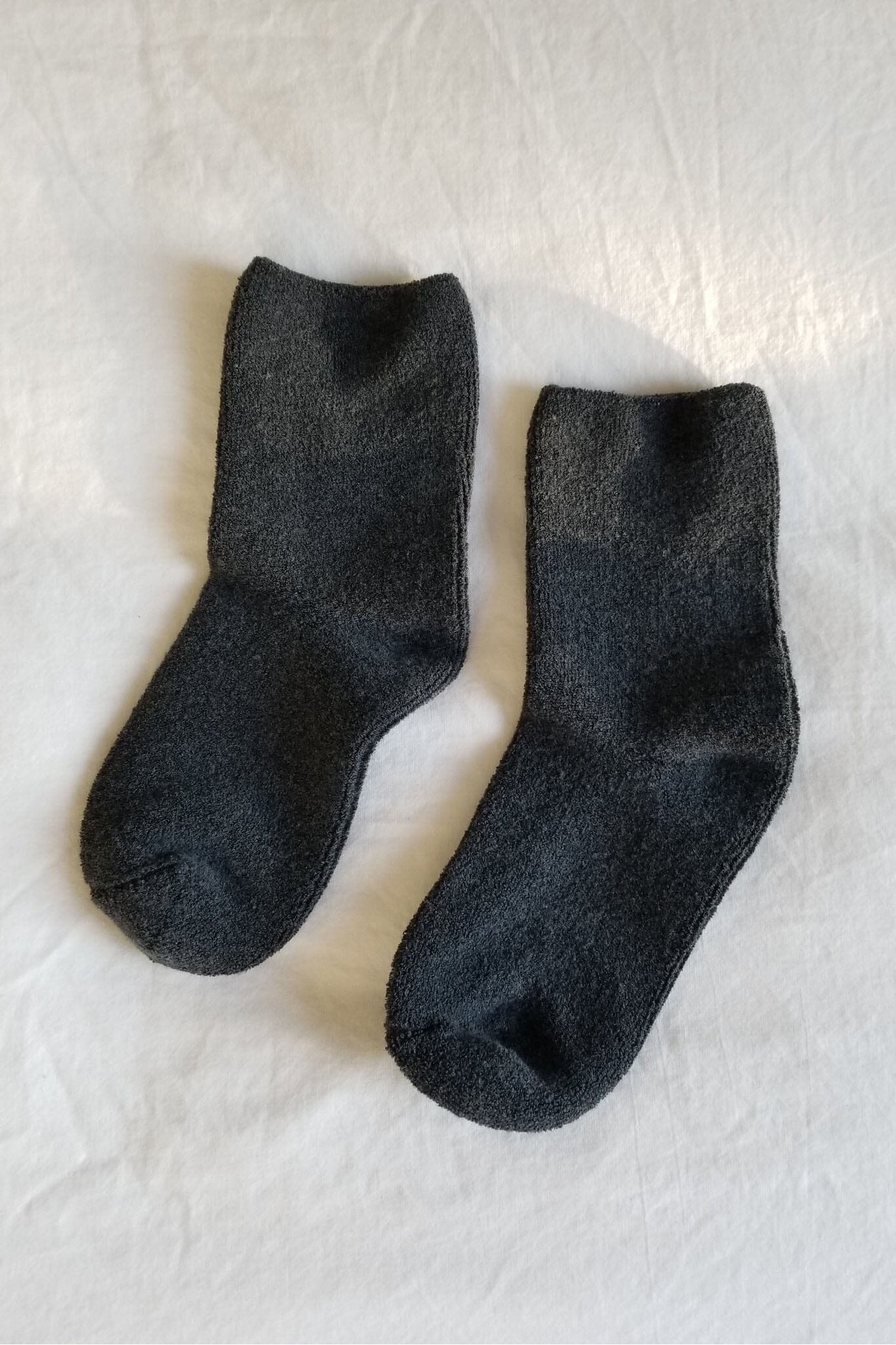 Pair of dark gray socks on a textured white surface