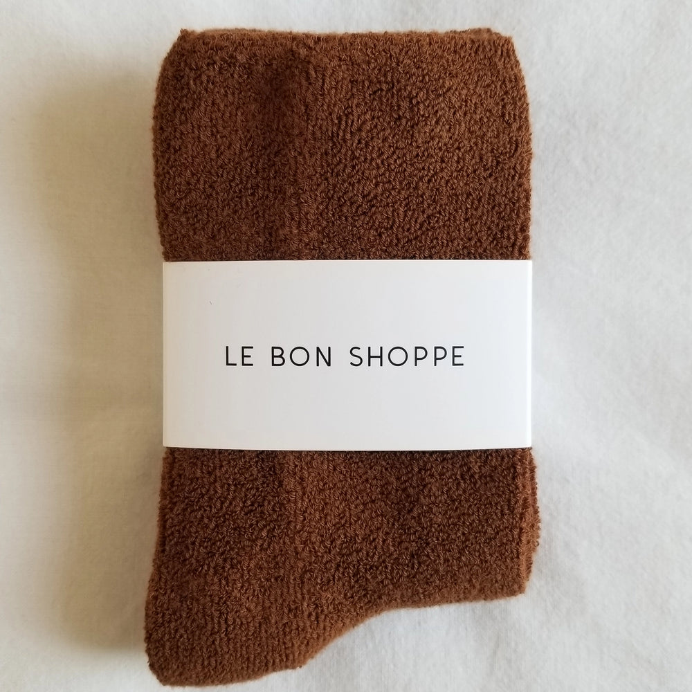 
                  
                    Pair of brown socks with a white label on a light background
                  
                
