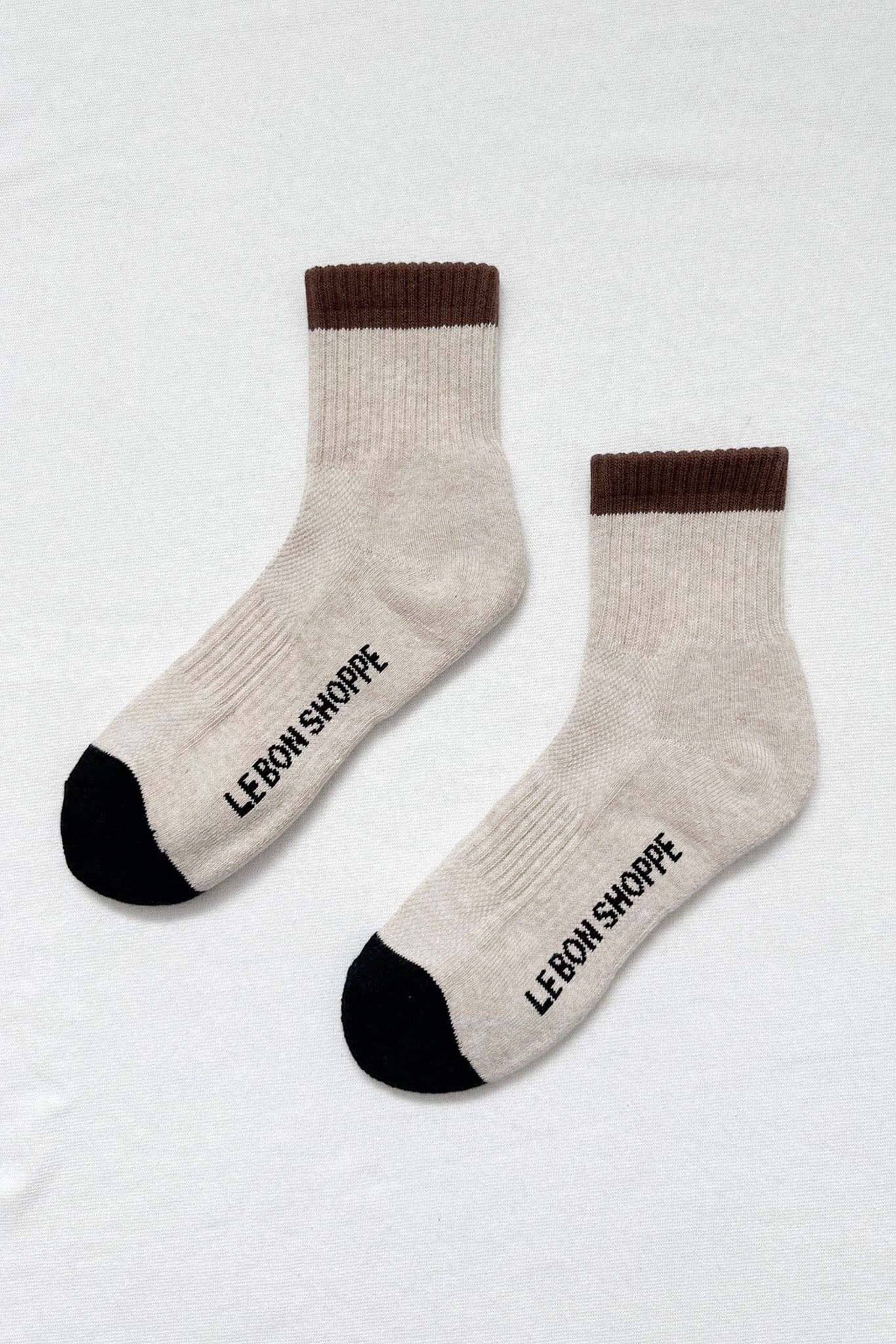 Pair of beige socks with brown accents and 'Le Bon Shoppe' branding on a light gray background