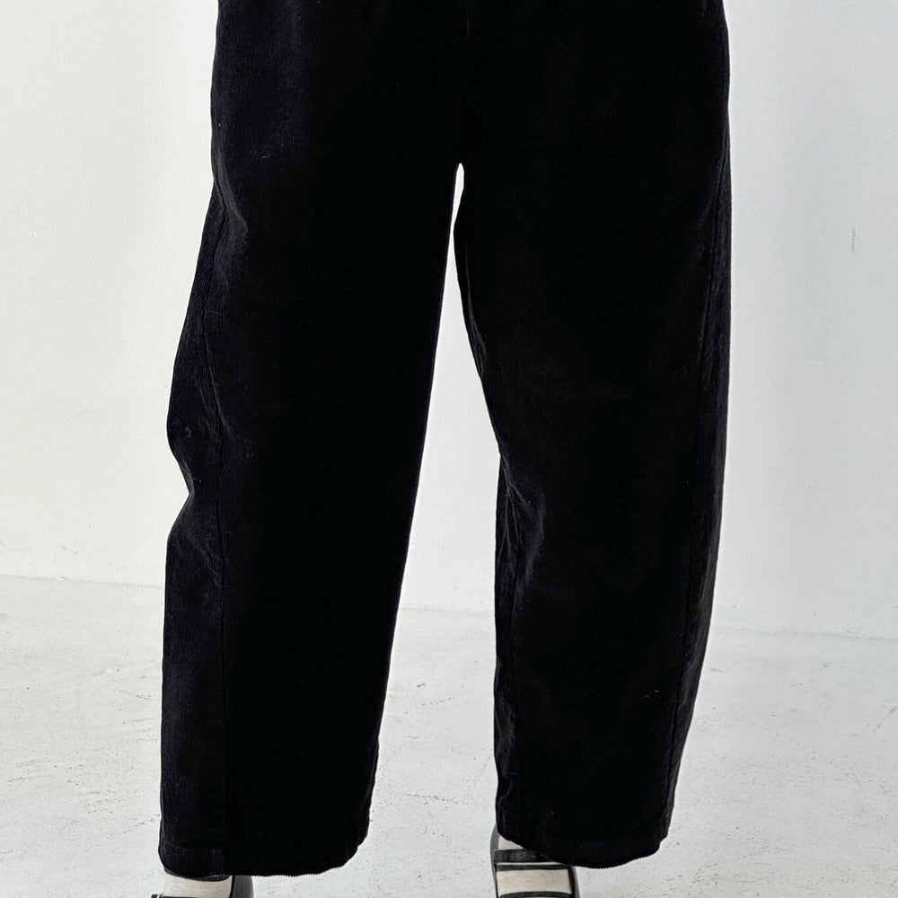 Person wearing black straight-leg pants on a white background