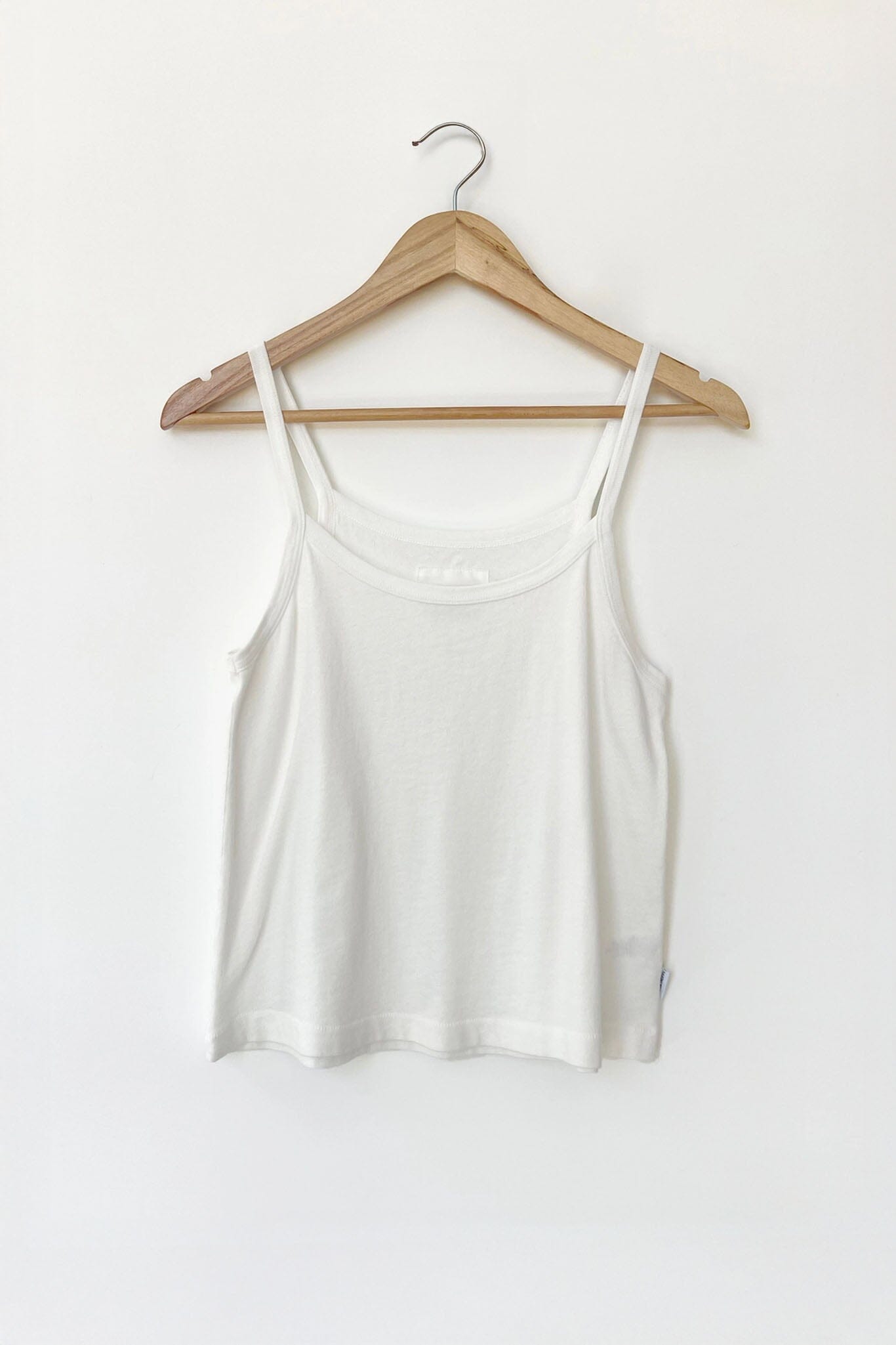 White tank top on a wooden hanger against a white background
