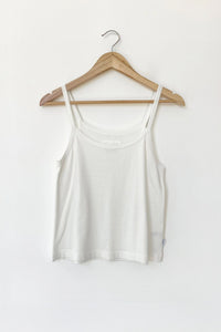 White tank top on a wooden hanger against a white background