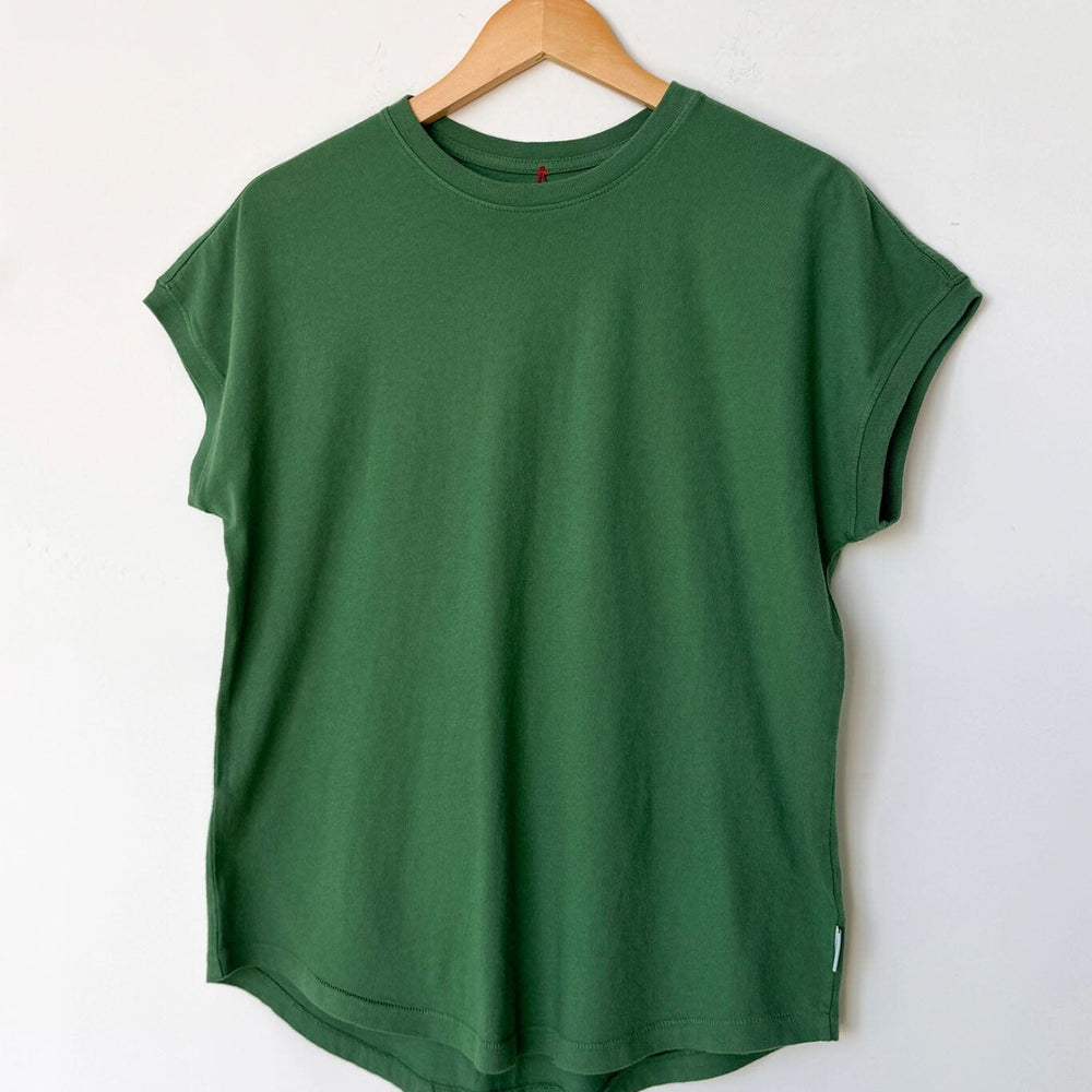 Green t-shirt on a wooden hanger against a white wall