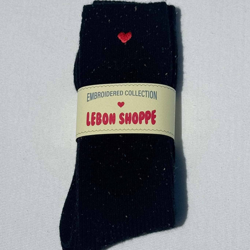 
                  
                    Black sock with red heart design and 'Lébon Shoppe' label on a light gray background
                  
                