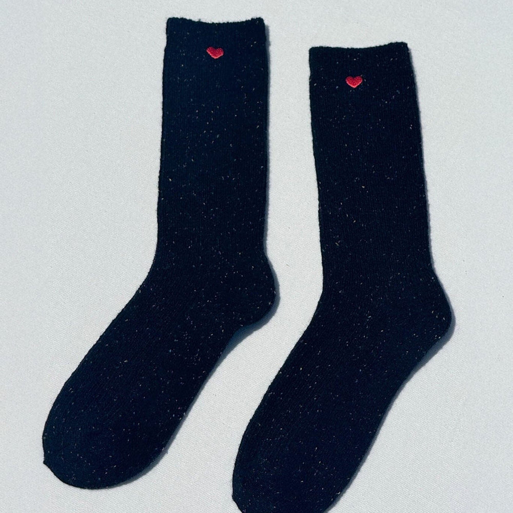 Pair of black socks with red hearts on a light gray background