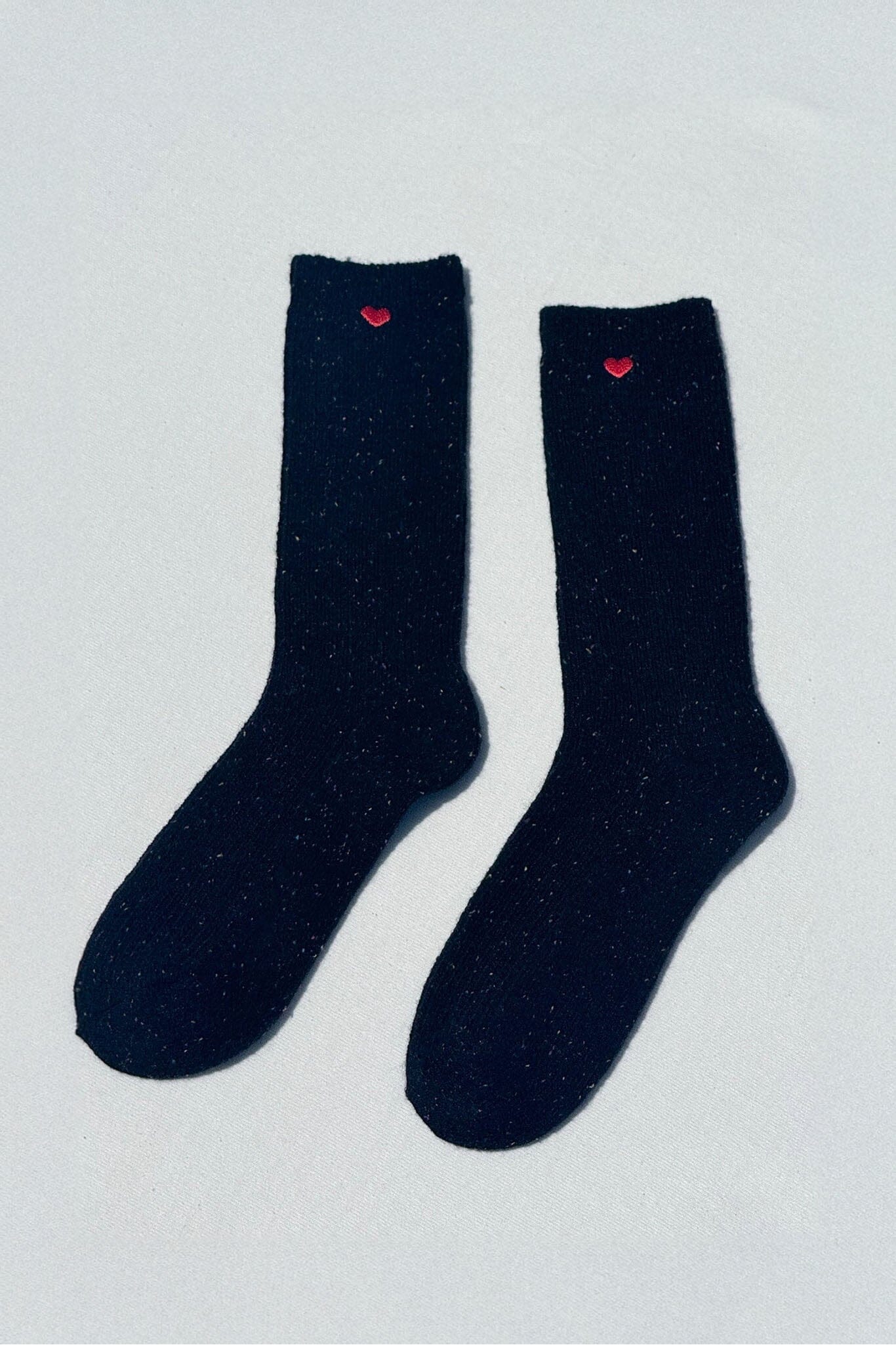 Pair of black socks with red hearts on a light gray background
