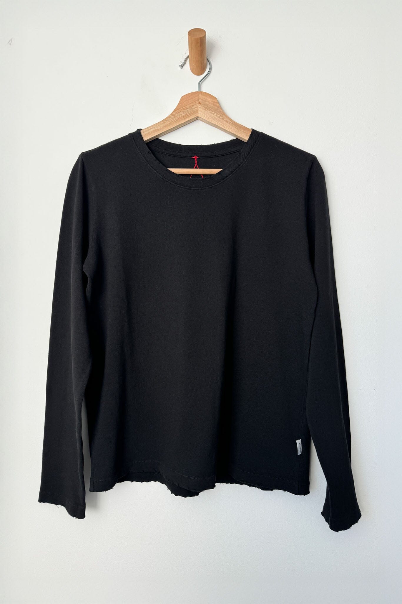 Black long-sleeve shirt on a wooden hanger against a white background