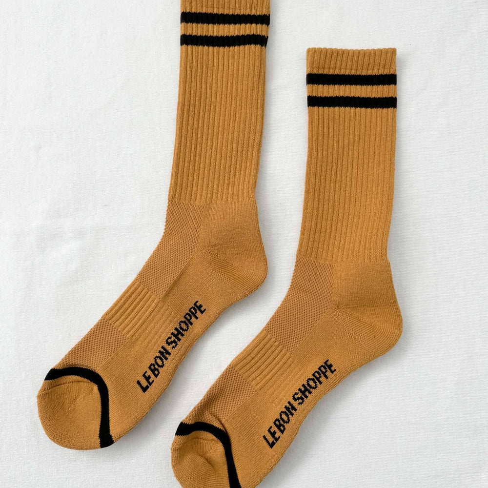 Pair of mustard yellow socks with black stripes and text on a white background