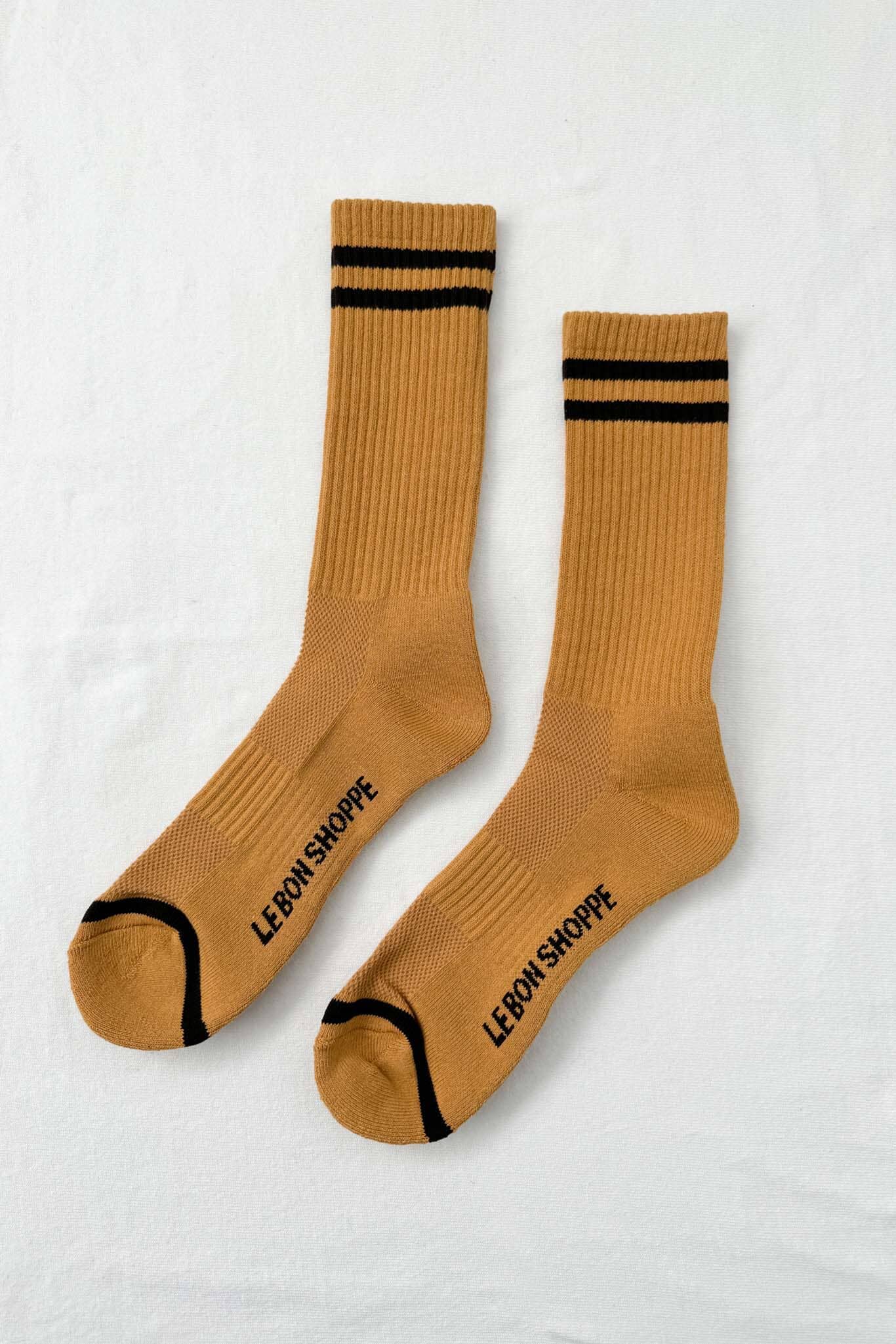 Pair of mustard yellow socks with black stripes and text on a white background