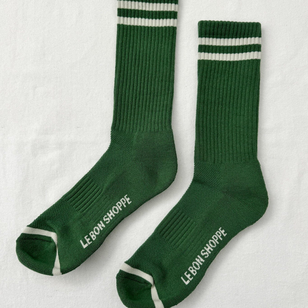 Green socks with white stripes and 'Le Bon Shoppe' branding on a light gray background