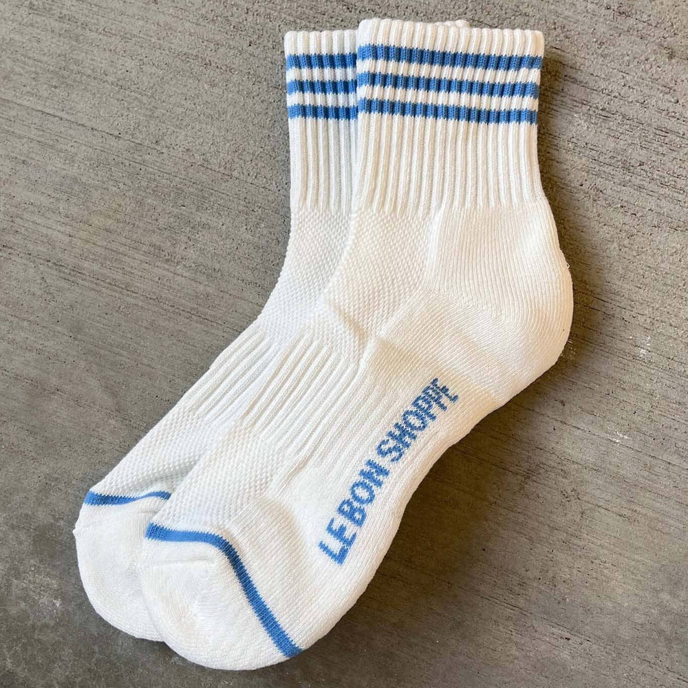 White socks with blue stripes and 'LeBon Shoppe' branding on a gray surface