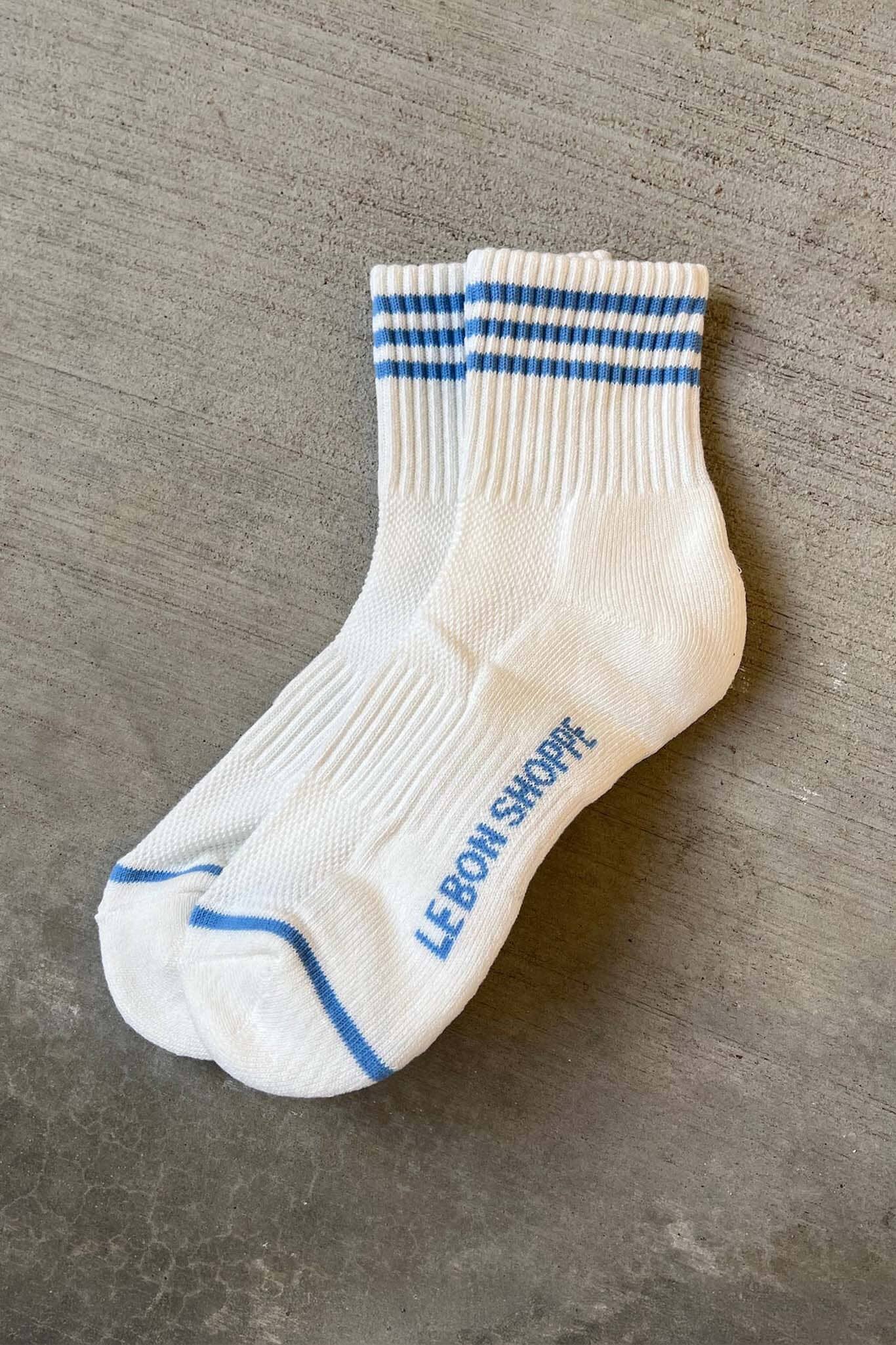 White socks with blue stripes and 'LeBon Shoppe' branding on a gray surface