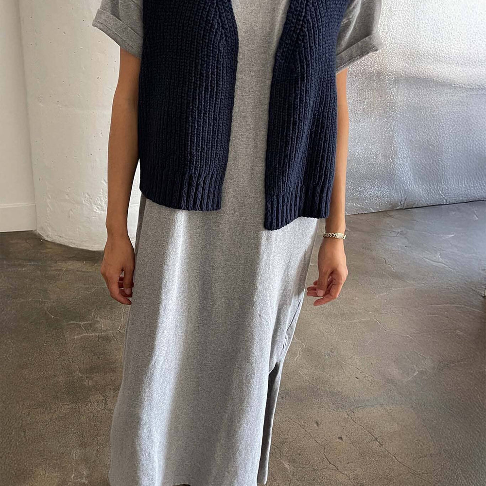 
                  
                    Person wearing a long gray dress with a navy cardigan over a gray shirt indoors.
                  
                