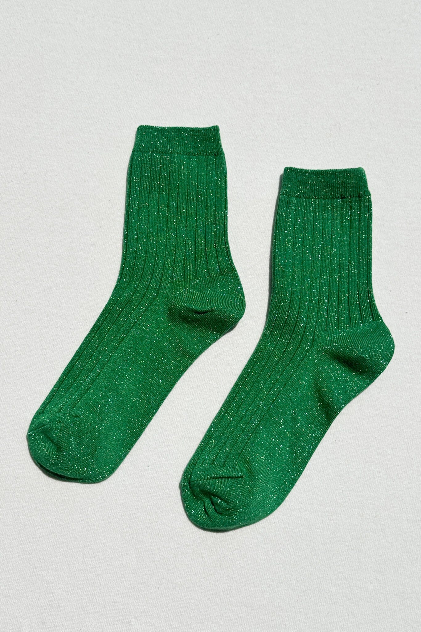 Pair of green sparkly socks on a light gray background