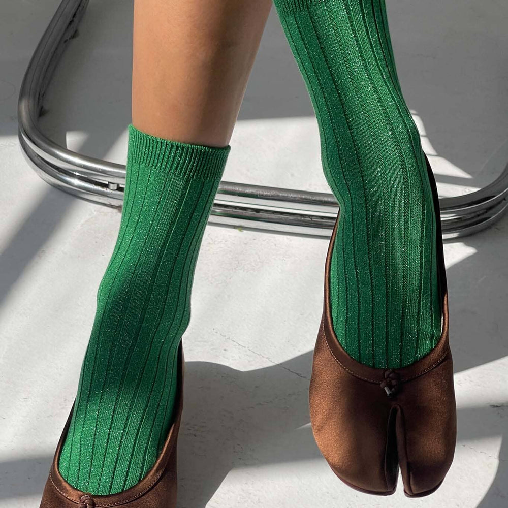 
                  
                    Green sparkle socks worn with brown shoes on a light background
                  
                