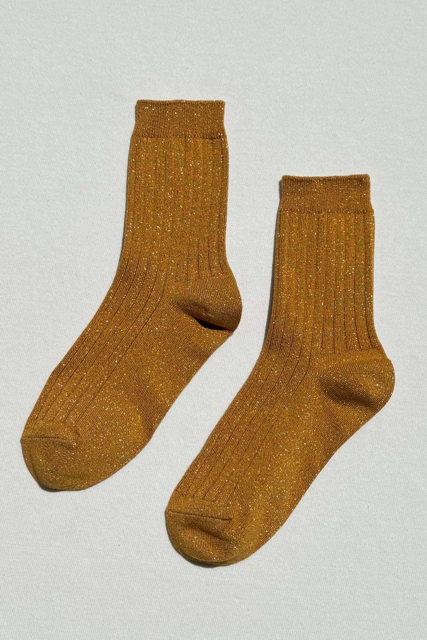 Pair of mustard yellow glitter socks on a light gray background